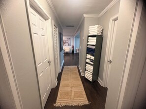 A hallway with a patterned rug, a stack of folded towels, and a door on the left. - Serene 4-bedroom house perfect for relaxing stays in Decatur near Atl downtown (Decatur)
