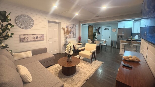 A modern living room with a sofa, coffee table, and chairs, a dining area with a table and chairs, and a kitchen with a refrigerator and bar stools. - Serene 4-bedroom house perfect for relaxing stays in Decatur near Atl downtown (Decatur)