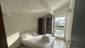 Un dormitorio con cama, armario y vistas al exterior.