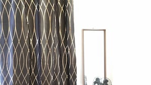 A bedroom with a bed, a wooden nightstand, a mirror, and a black heater. - Mags Charming 35m² Apartment in Vienna's Heart (Vienna)