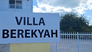 Skilt med 'Villa Berekyah', hvid bygning i baggrunden.
