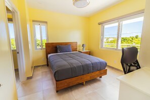 Ein Schlafzimmer mit Bett, Nachttisch, Lampe und Blick durch das Fenster.
