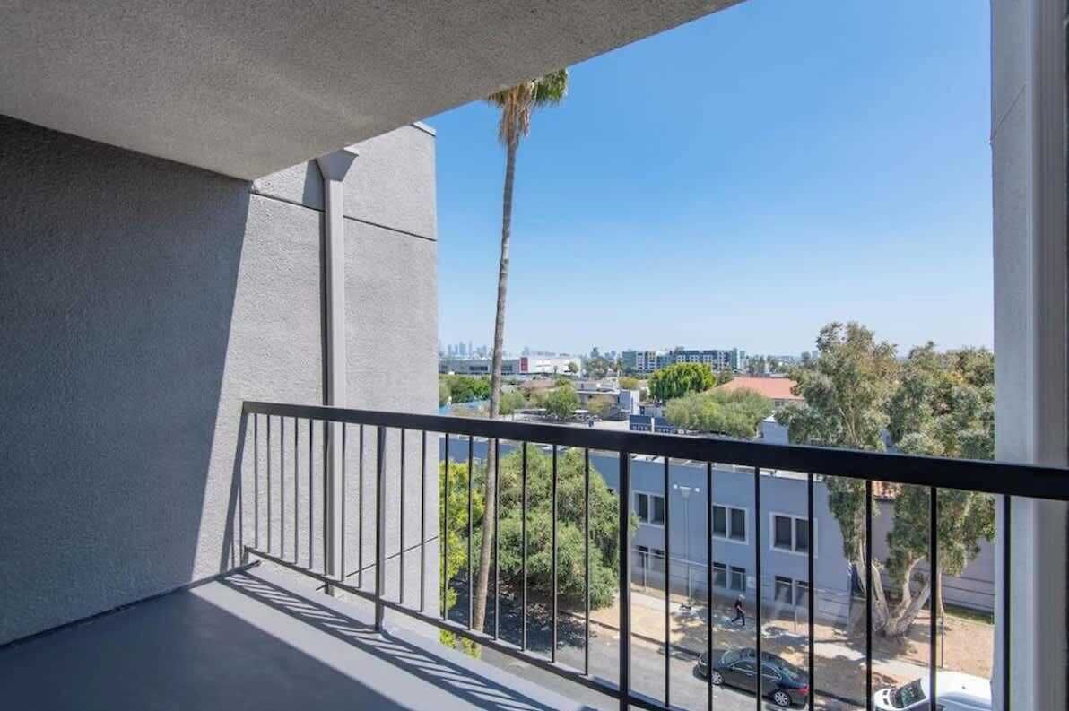Un balcón con vista a un paisaje urbano, con edificios y una palmera.