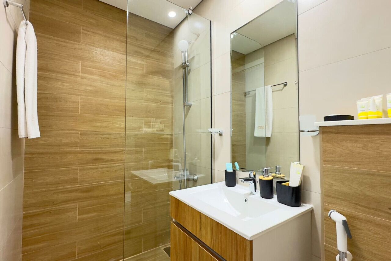 Une salle de bain moderne avec une douche à parois de verre, un meuble-lavabo en bois et un miroir au-dessus du lavabo.