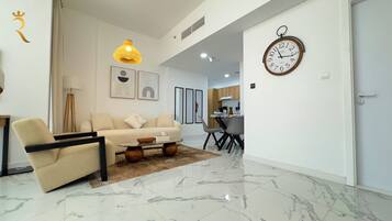 A modern living room with a sofa, coffee table, and a dining area with chairs and a table.