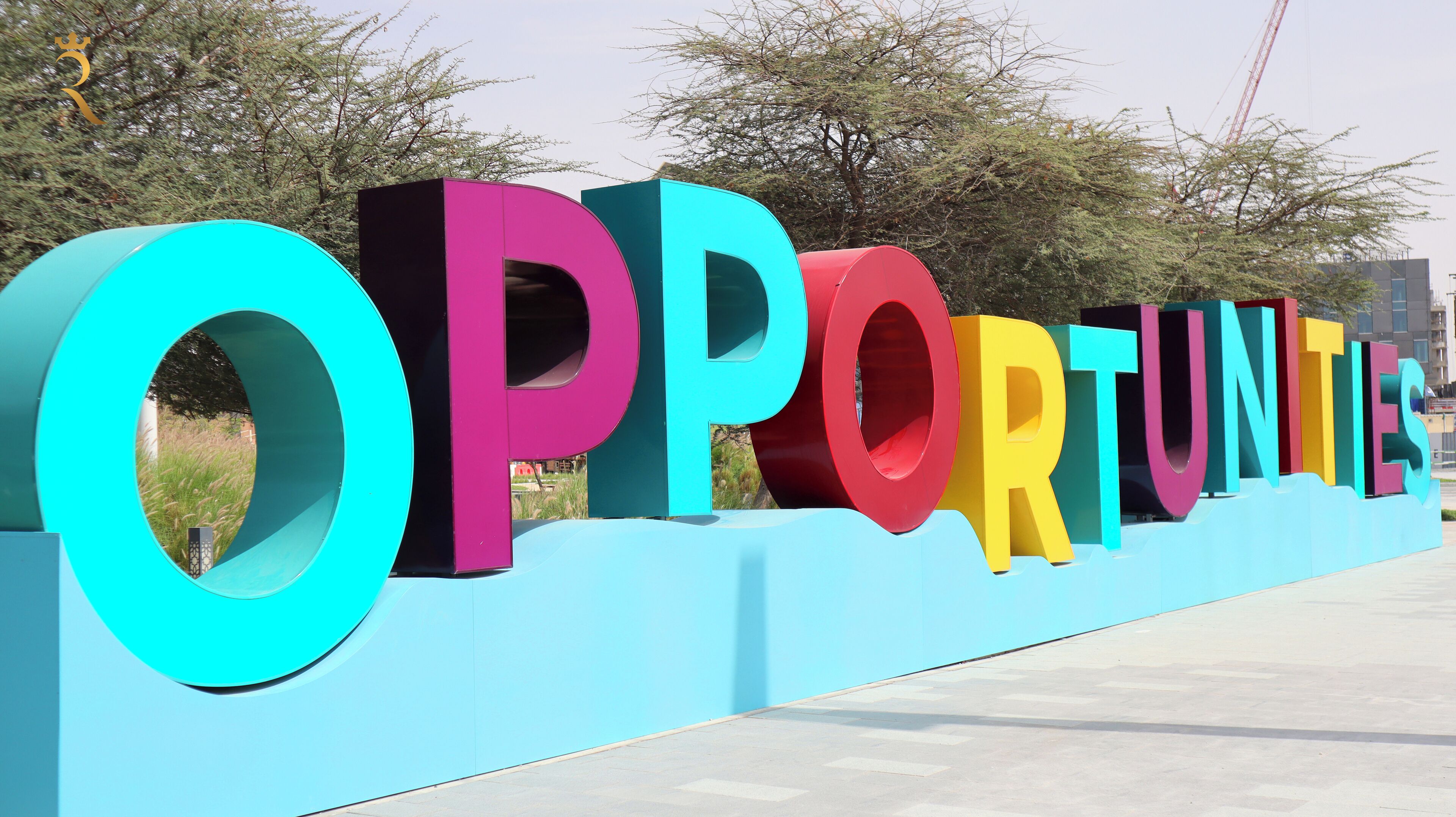 Grandi lettere colorate che compongono la parola 'OPPORTUNITIES' su una piattaforma blu.