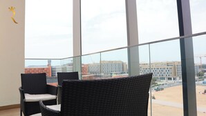 A balcony with wicker chairs and a view of a construction site. - Masdar Oasis 2 Design Apartments By Rhh (Abu Dhabi)