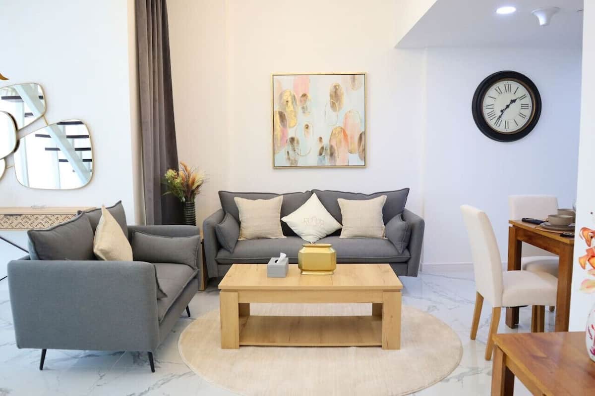 A modern living room with a grey sofa, a wooden coffee table, and a dining area with a wooden table and chairs.