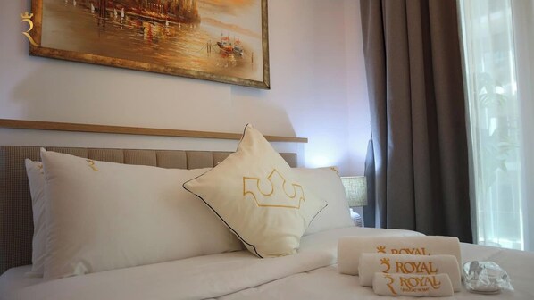 Une chambre d’hôtel avec un lit, des oreillers, un tableau et une fenêtre avec des rideaux.