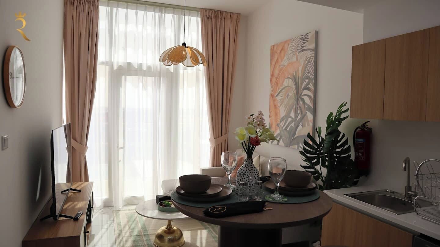 A modern kitchen with a dining area, a large window with curtains, a wall-mounted clock, and a painting.