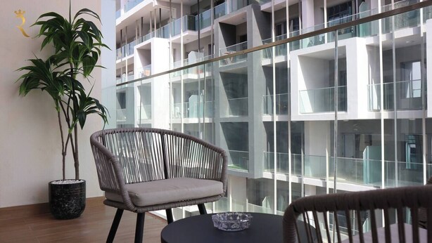 Un intérieur moderne avec un balcon en verre, une plante en pot et des meubles en osier.