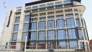 Un immeuble à plusieurs étages, reconnaissable à son grand panneau indiquant « Reportage », à ses larges fenêtres et à son architecture moderne.