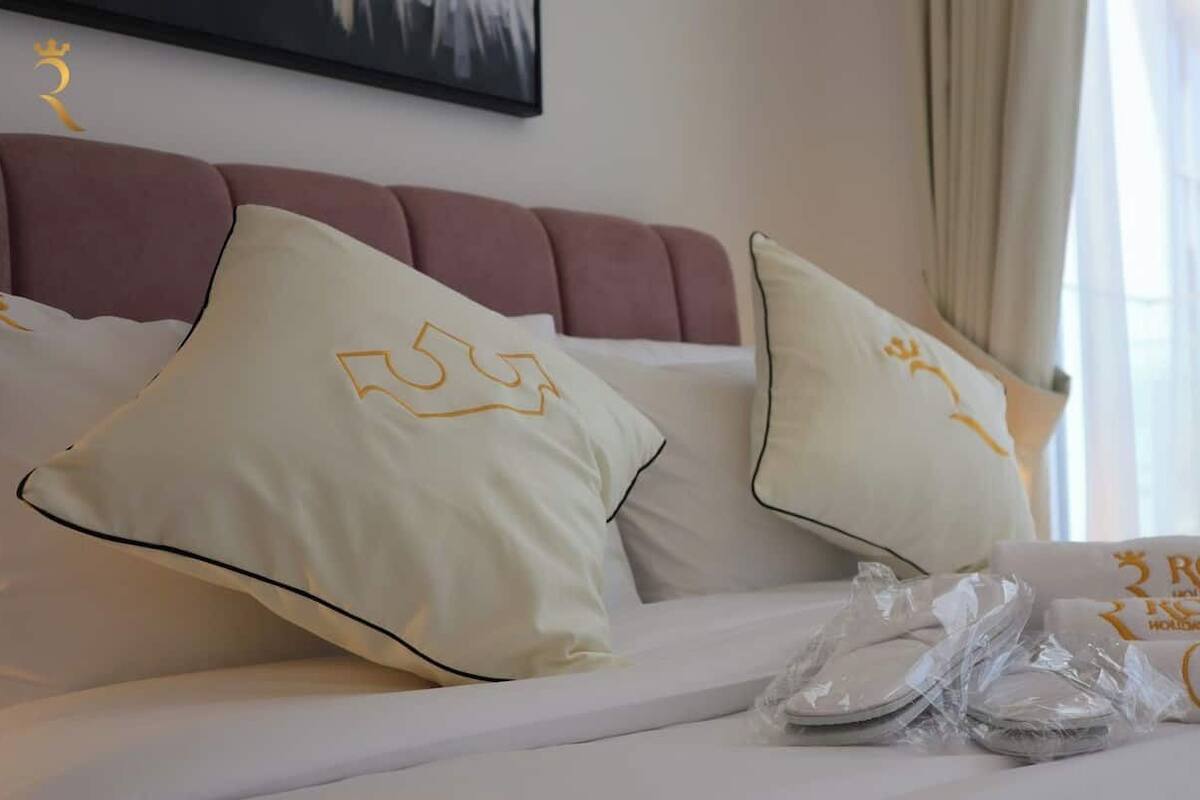 A hotel room with a bed, pillows, and a set of towels.