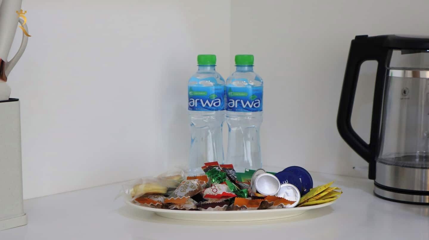 Ein Teller mit Snacks und zwei Wasserflaschen, ein Wasserkocher und eine weiße Wand.