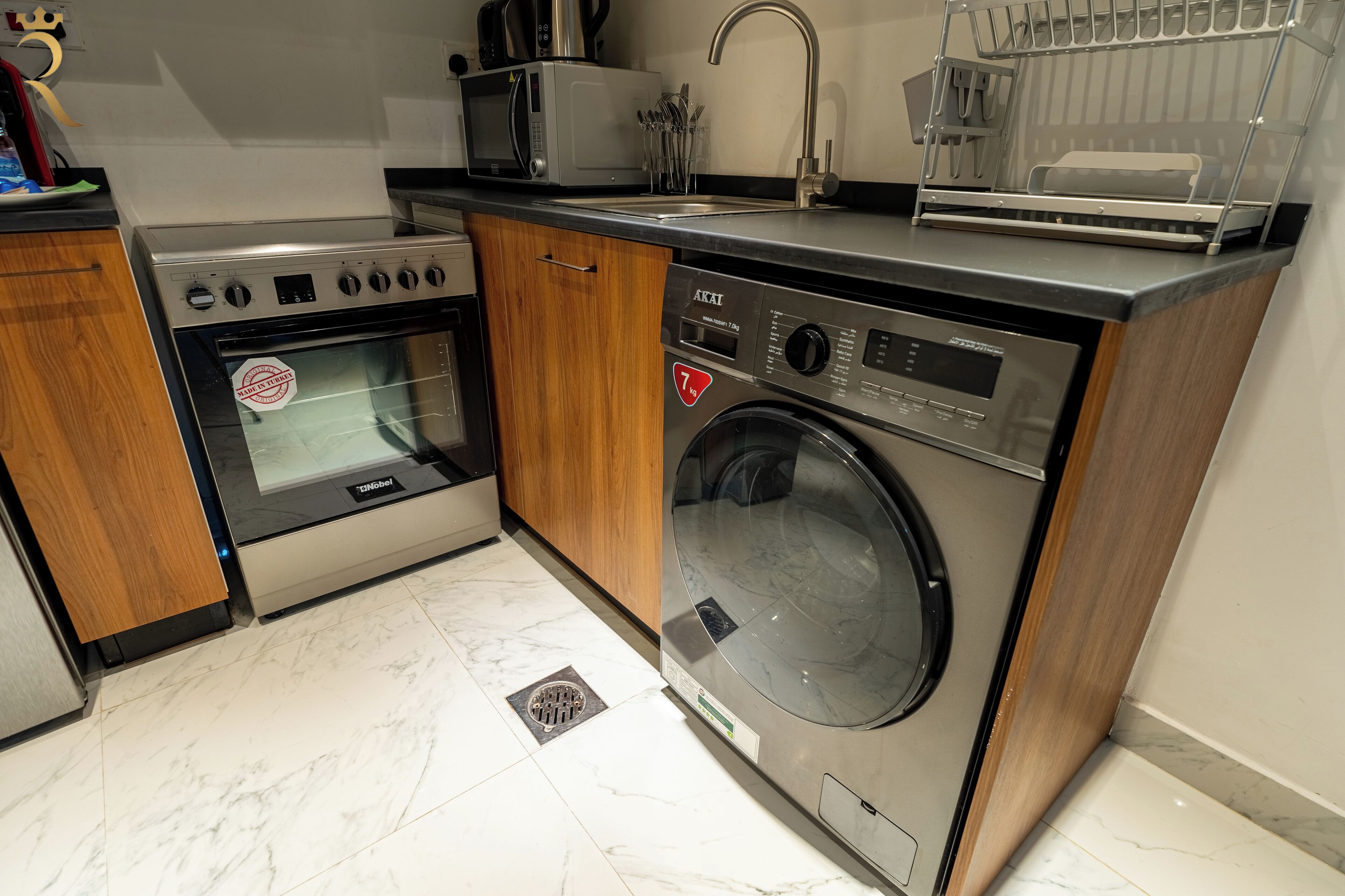 Une cuisine compacte équipée d’un four, d’un micro-ondes et d’un lave-linge intégrés.