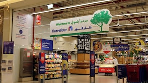 Un supermercato Carrefour con un grande cartello di benvenuto, scaffali pieni di prodotti e insegne promozionali che pubblicizzano offerte e prezzi bassi.