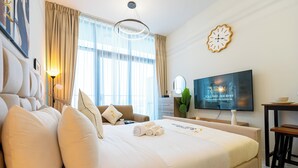 A hotel room with a large bed, a television, a clock, and a window with curtains. - Masdar The Gate Studio (Abu Dhabi)