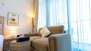 A modern hotel room with a beige sofa, a side table with a lamp, and a framed artwork on the wall. - Masdar The Gate Studio (Abu Dhabi)