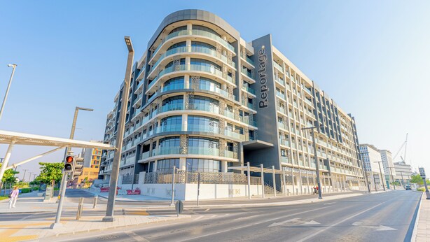 Un hôtel moderne à la façade incurvée, doté de nombreux balcons et d’une entrée imposante.
