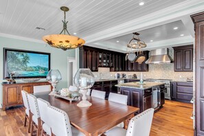 A spacious kitchen with dark wood cabinets, a large island with seating, and modern appliances. - Luxurious Home Located In Venetian Shores (Islamorada)