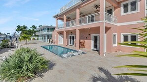 A two-story house with a pool, balconies, and a view of the marina.