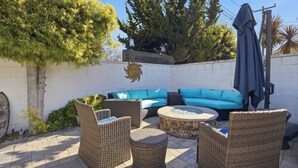 An outdoor patio with wicker furniture, a blue sofa, and a round table. - Fabulous 2-bedroom house with Pool and spa in sunny Long Beach (Long Beach)