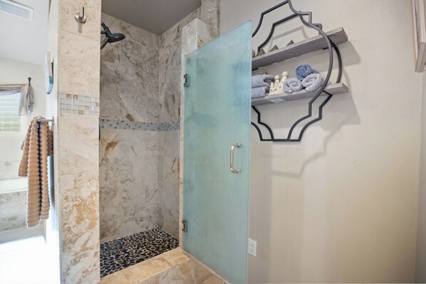 Un baño con ducha, un perchero y un estante con toallas.