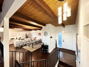 A modern kitchen with white cabinets, a dining area with bar stools, a staircase, and a wooden ceiling. - 4 Bed Sunset Abode with Open-Plan & Stunning Views (Los Angeles)