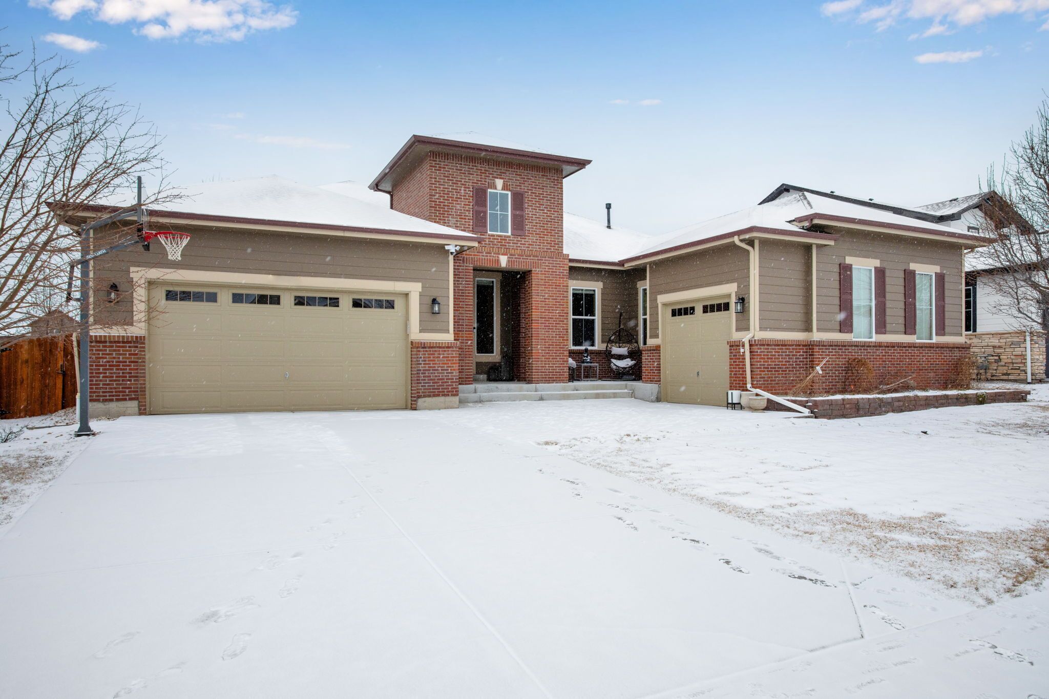 A two-story house with a garage, a brick section, and a covered driveway.