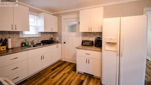 Una cocina con armarios blancos, microondas, tostadora y refrigerador.