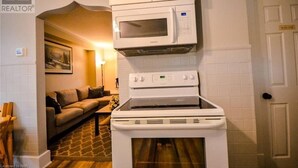 Una cocina compacta con microondas, horno y armarios.