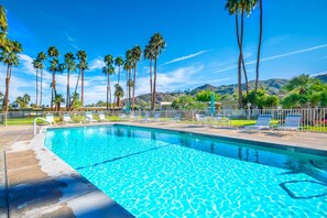 A clear blue pool with lounge chairs and palm trees, surrounded by a fenced area and a mountain backdrop. - Palm Springs ~ Pool, Hot Tub (Palm Springs)