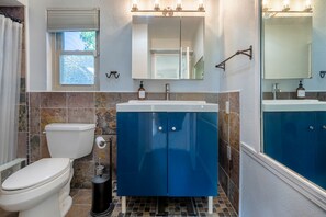 A bathroom with a toilet, a sink with a mirror above it, and a window with blinds. - Palm Springs ~ Pool, Hot Tub (Palm Springs)