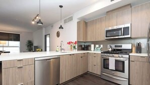 Eine moderne Küche mit Holzschränken, Edelstahlgeräten und einer zentralen Kochinsel.