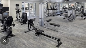 Ein Fitnessstudio mit verschiedenen Trainingsgeräten, darunter Laufbänder, Crosstrainer und Kraftgeräte.
