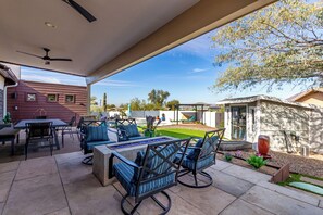 Ein überdachter Patio-Bereich mit Gartenmöbeln, einem Pool und Blick auf den Garten.