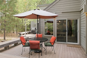 A deck with a table and chairs, a grill, and a covered area with an umbrella. - Black Butte Ranch Golf Home 155 (Sisters)