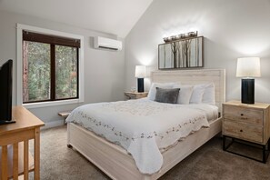 Bedroom with vaulted ceilings, a light wood bed, and views of surrounding trees. - Black Butte Ranch Golf Home 155 (Sisters)