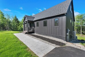 Een modern gebouw met een grijze gevel, een overdekte veranda en een verhard pad.
