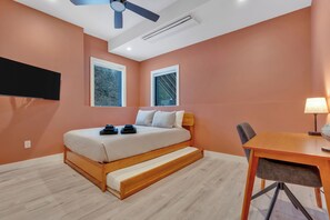 A bedroom with a bed, a desk, two windows, a ceiling fan, and a TV mounted on the wall. - Lakefront Scandinavian Vacation Rental with Private Dock, Hot Tub & Kayaks<br> Brand New, modern home with high end amenities - close to Ogunquit, Kennebunkport and Wells Beaches. (Alfred)