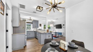 Una cocina moderna con armarios grises, una isla central y un comedor con una mesa dispuesta para cuatro.