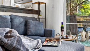 Una sala moderna con un sofá gris, una mesita redonda y una silla de mimbre.