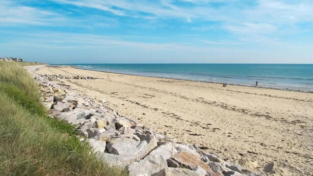 Ein Strand mit felsiger Küstenlinie und blauem Himmel.