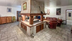 Ein geräumiger Wohnbereich mit Kamin aus Stein, Ledermöbeln und Kunstwerken an den Wänden.