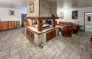 Ein geräumiger Wohnbereich mit Kamin aus Stein, Ledermöbeln und Kunstwerken an den Wänden.