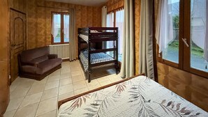 Ein Zimmer mit einem Etagenbett, einer Schlafcouch, einem Heizkörper und einem fenster mit Vorhängen.