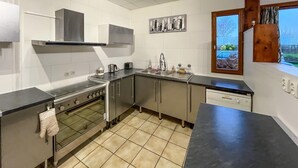 Eine moderne Küche mit Edelstahlgeräten, gefliestem Boden und einem Fenster mit Blick ins Freie.