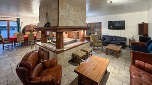 Ein geräumiges Wohnzimmer mit Kamin, Ledersofas, einem Holztisch und einem Fernseher.