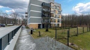Een modern meerlaags woongebouw met balkons, een geplaveid voetpad en een omheind tuingedeelte.
