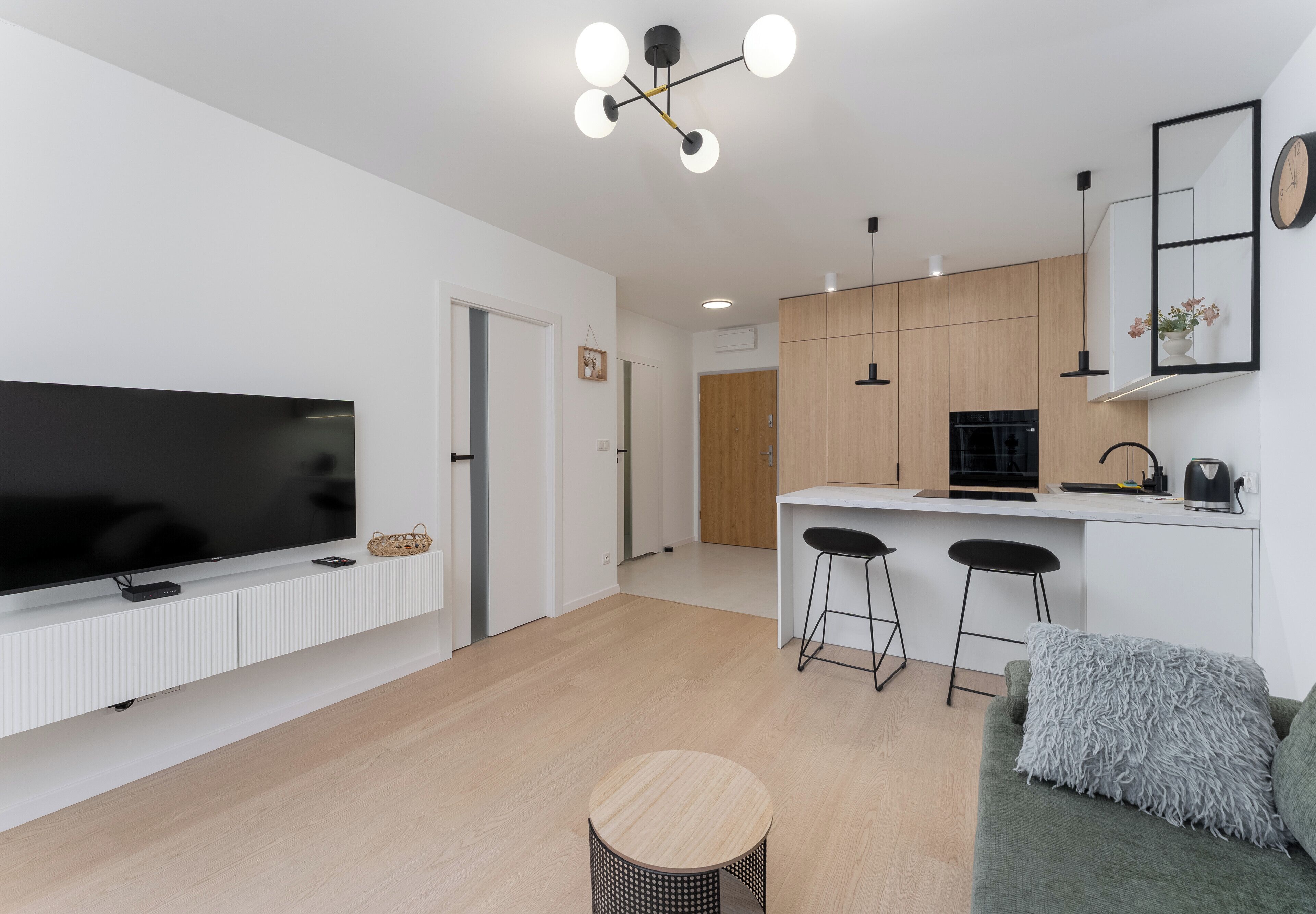 A modern living room with a flat-screen TV, a round coffee table, and a sofa with a throw pillow.
